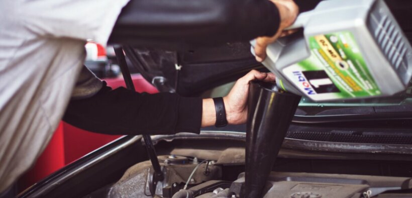 an auto technician pours mobil 1 synthetic motor oil into a car's engine