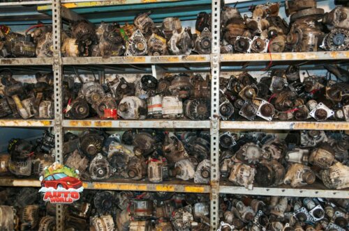 used alternators from wrecked cars on a shelf at an auto salvage yard